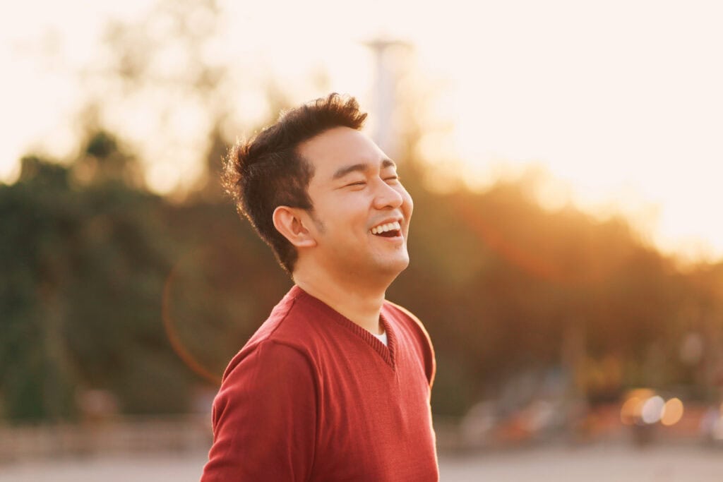 Young man smiling outdoors after attending westminster drug rehab.